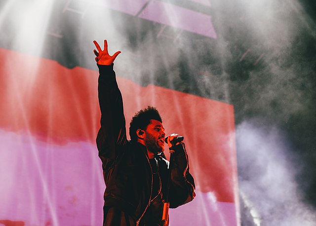 The Weeknd raising his hand while singing